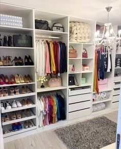 an organized closet with white shelving and lots of shoes on the floor, chandelier hanging from the ceiling