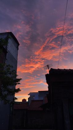 the sky is pink and purple as the sun sets over some buildings in an alleyway