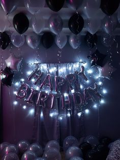 a birthday party with balloons and streamers on the wall in front of an arch that says happy birthday