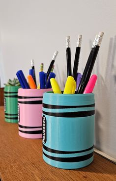 three cups with pens and pencils in them