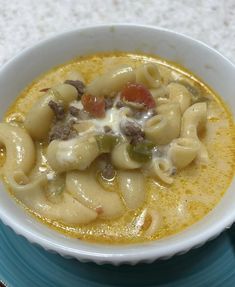 a white bowl filled with pasta soup on top of a blue plate