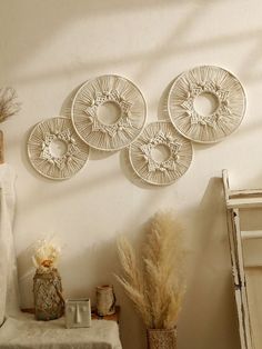 three circular wall hangings on the wall above a table with vases and plants