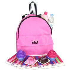 a pink backpack sitting on top of a table filled with cupcakes