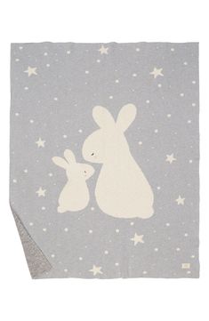 a blanket with two rabbits on it and stars in the sky behind them, one is white