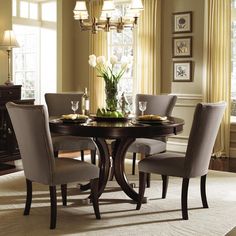 a dinning room table with chairs and a vase on top of it in front of a window