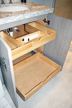 an open cabinet in a bathroom with marble counter tops and wood drawers on both sides