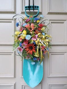 a bouquet of flowers hanging on the side of a door with a blue ribbon attached to it