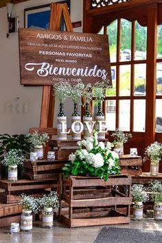 flowers are arranged on wooden crates in front of a sign that reads, benvendos love