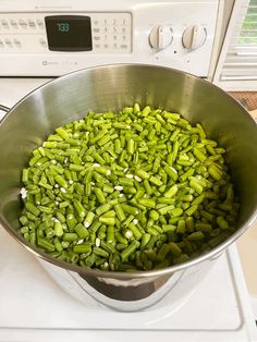 green beans are being cooked in a pot on top of the stove, ready to cook