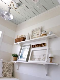 a white shelf with pictures and other items on it in the corner of a room