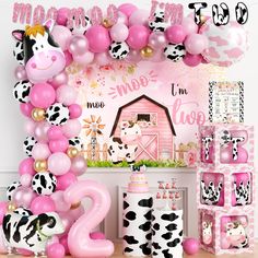 a pink and black cow themed birthday party with balloons, streamers, decorations, and farm animals