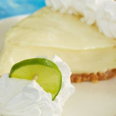 a slice of key lime pie on a plate with whipped cream and a lime wedge