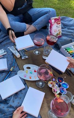 people sitting on the ground painting with watercolors and paintbrushes in front of them