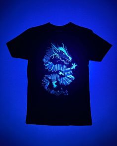 a t - shirt that is lit up in blue and has a dragon on it