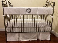 a baby crib with white sheets and monogrammed bedding on the bottom