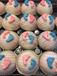 cupcakes decorated with pink, blue and white icing are in a box