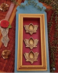 three framed pictures with flowers and leaves in them on top of a red table cloth