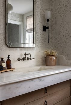 a bathroom sink sitting under a mirror next to a wooden cabinet and counter top with soap dispenser on it