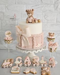 a baby shower cake with teddy bears and cookies on the table next to it,