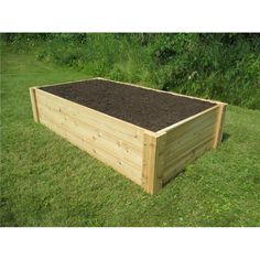 a wooden raised garden bed with soil in the middle and grass on the other side