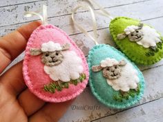 three small sheep ornaments are being held by someone