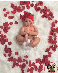 a baby with red paint on it's face sitting in a circle of petals