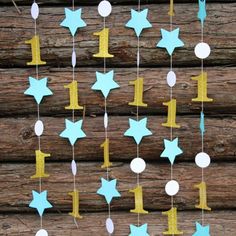 a mobile with stars hanging from it's sides on a wooden wall next to logs