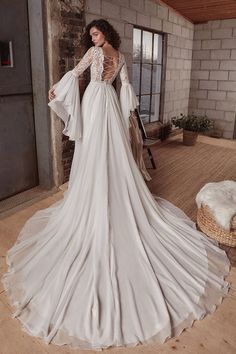 a woman in a wedding dress standing on a wooden floor next to a brick wall