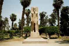 a large statue in the middle of palm trees