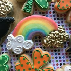 several decorated cookies are arranged on a polka dot tablecloth with shamrocks, rainbow and clouds