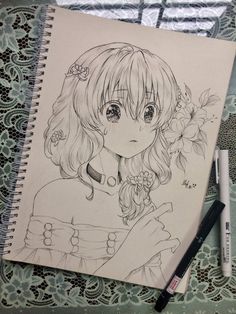 a drawing of a girl with long hair and flowers on her head, next to a pen