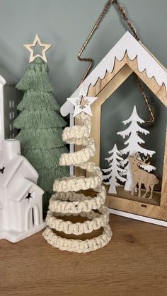 a christmas tree made out of toilet paper and some other items on a shelf next to a small house