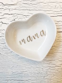 a white heart shaped dish with the word mamma written on it in cursive writing