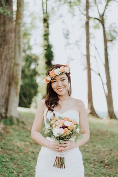 a woman in a white dress holding a bouquet of flowers and smiling at the camera