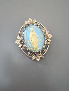 "Vintage Jewelry - Vintage Brass - Blue Brooch - Mother Mary Jewelry - Catholic Brooch - Religious Jewelry - handmade jewelry This is such a pretty brooch! Vintage brass setting embellished with a vintage light blue and gold vintage cameo of the Mother Mary. Exquisite detail with a rich patina on the brass. This is a real special piece. Chloe says, \"Wear it and feel fabulous!\" The pendant is 1 1/4\" long Thanks for visiting Chloe's" Antique Blue Collectible Brooches, Antique Handmade Blue Brooches, Vintage Blue Enamel Pin Gift, Blue Brooch Lapel Pin As Gift, Blue Brooch Pin For Gift, Blue Brooch Pins As A Gift, Blue Brooch Pin As Gift, Blue Brooch Pins For Gift, Mary Jewelry