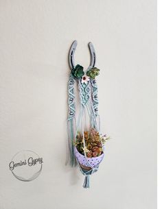 a wall hanging planter with succulents and flowers