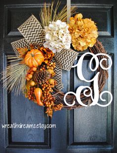 a wreath with flowers and leaves hanging on the front door