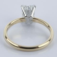 a yellow gold engagement ring with a princess cut diamond in the center, on a white background