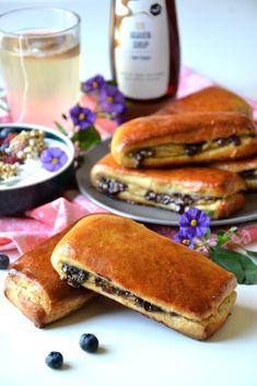 two plates with blueberry pancakes on them next to a bottle of syrup and flowers