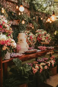 a table topped with a white cake surrounded by lots of flowers