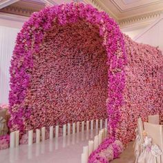 pink flowers are covering the walls and ceiling in this wedding ceremony room, which is decorated with candles