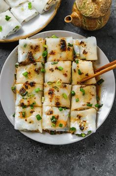 some food on a plate with chopsticks next to it and another dish in the background