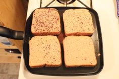 four pieces of bread sitting on top of a black pan over an oven burner