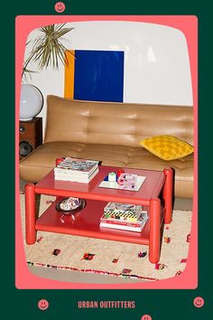 a red coffee table sitting in front of a brown couch with books on top of it