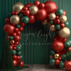 an arch made out of red, green and gold balloons with pine cones on the bottom