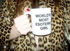 a woman is holding a coffee mug in her right hand while wearing leopard print coat