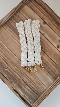 two white rope bracelets sitting on top of a wooden table