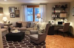 a living room filled with furniture and a large window covered in curtains on top of a hard wood floor