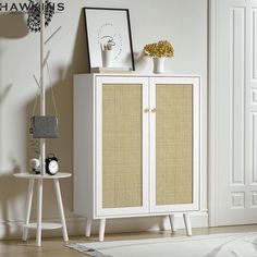 a white cabinet sitting next to a clock on top of a wooden table in a room