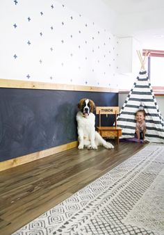 a dog sitting in front of a chalkboard with a teepee tent next to it